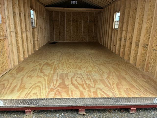 Interior of 12x24 Smartside A‑Frame single garage (Model 2051S) with unfinished stud walls, plywood floor, and two side windows; ready for optional 4 ft loft or shelving